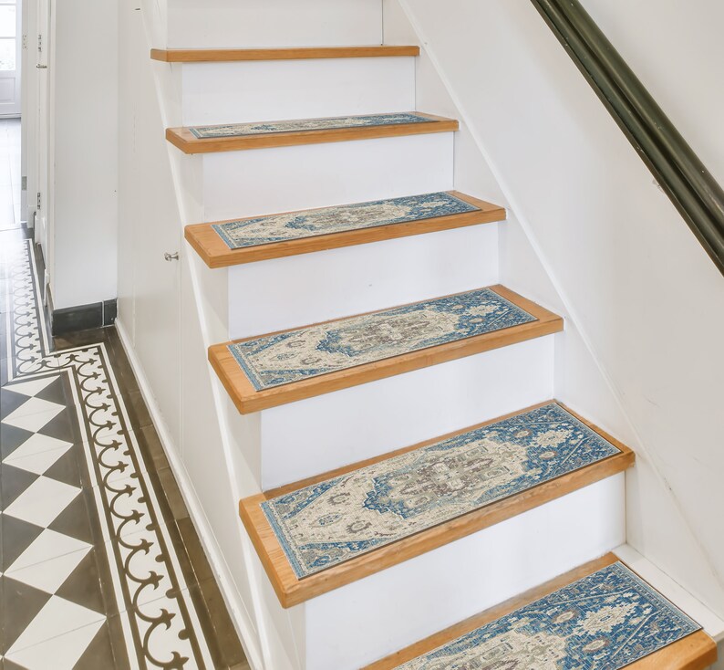 Puede incluir: Escalera con contrahuellas blancas y pelda&ntilde;os de madera. Cada pelda&ntilde;o presenta una alfombra rectangular con un patr&oacute;n ornamental azul, beige y marr&oacute;n. La escalera tiene una barandilla negra y est&aacute; en un interior bien iluminado.