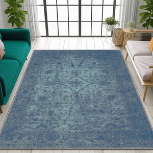 May include: A blue and green distressed area rug with a vintage pattern. The rug is laid out on a light wood floor in a living room setting.