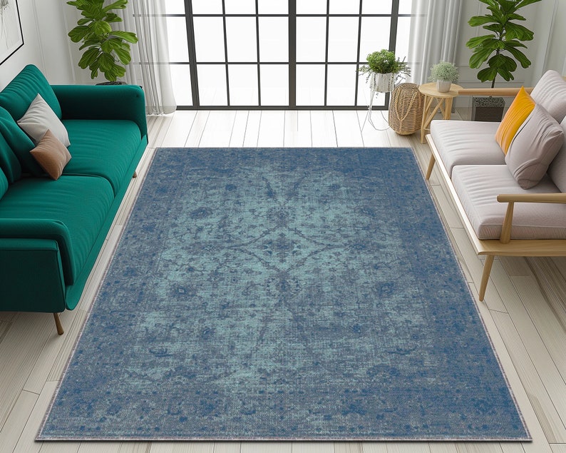 May include: A blue and green distressed area rug with a vintage pattern. The rug is laid out on a light wood floor in a living room setting.