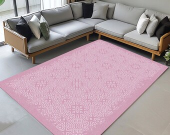 May include: A pink area rug with a white geometric pattern. The rug is in a living room with a light gray sectional sofa.