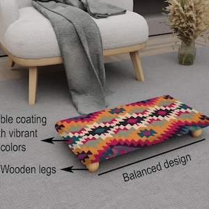 May include: A rectangular footstool with a vibrant geometric pattern in shades of orange, pink, teal, and purple. It features a durable coating and wooden legs. The design is balanced, and the footstool is placed on a gray carpet.