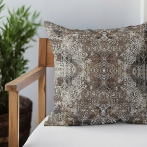 May include: A decorative throw pillow with a brown and white geometric pattern. The pillow is sitting on a wooden chair with a white cushion.
