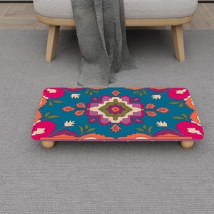 Puede incluir: Una taza de cerámica blanca con un asa negra y el texto "But First, Coffee" en negrita negra. La taza se encuentra sobre un fondo borroso, sugiriendo un ambiente acogedor.