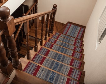 May include: A set of eight red, blue, and gray patterned stair treads with a geometric design. The treads are placed on a wooden staircase.