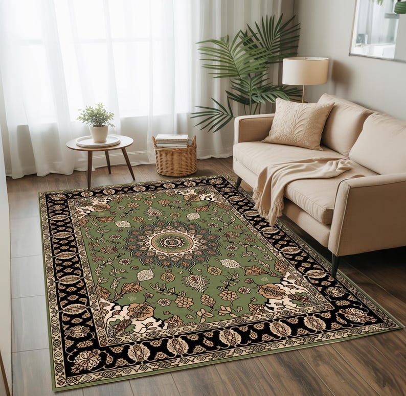 a cozy living room with a large, ornate rug featuring a floral design in shades of green and black. The rug is placed on a wooden floor, and a beige sofa is positioned against the wall. A small table with a plant and a lamp is located next to the sofa, and a window with white curtains allows natural light to enter the room.