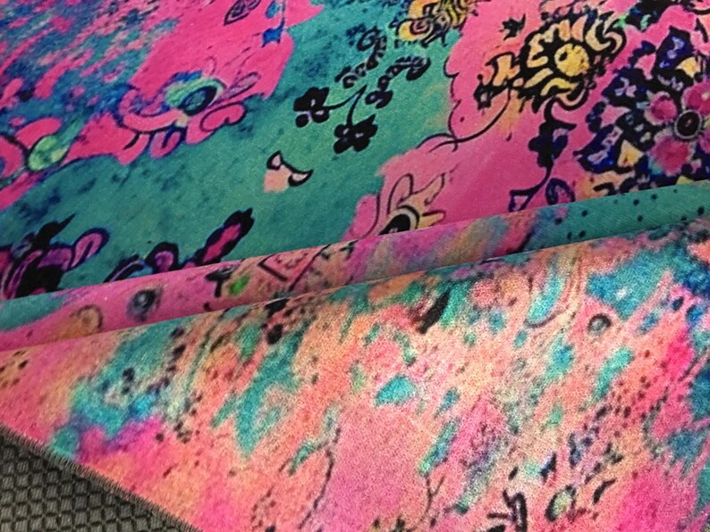 a vibrant, colorful fabric with a pattern of flowers and abstract shapes in various shades of pink, blue, green, and yellow.