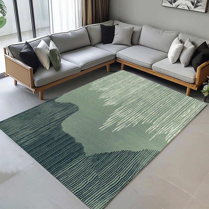 May include: A green and blue abstract area rug with a striped pattern. The rug is laid out on a light gray tiled floor in front of a gray sectional sofa.