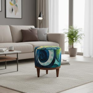 Op de afbeelding: Een ronde poef met een levendig bekledingspatroon van wervelende blauwe, turquoise en limoengroene vormen. De zitting rust op vier taps toelopende houten poten in een middenbruine afwerking, wat zorgt voor een stabiele basis voor dit meubelstuk.