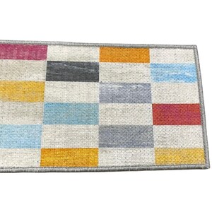 a colorful rug with a geometric pattern of squares in various shades of gray, blue, orange, and red.