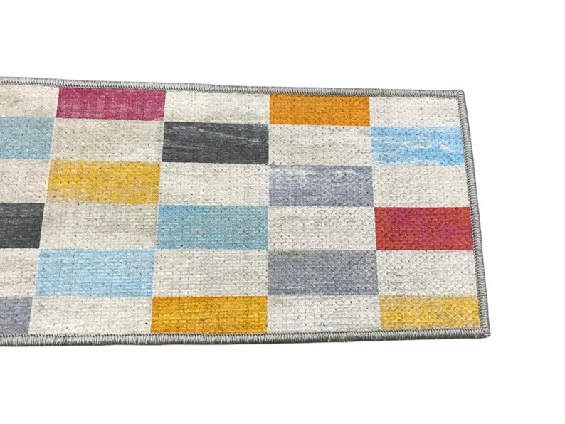 a colorful rug with a geometric pattern of squares in various shades of gray, blue, orange, and red.
