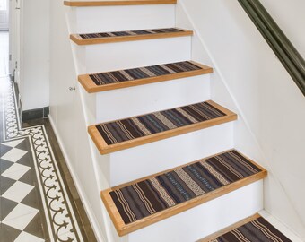 May include: A set of five brown and blue patterned stair treads with a geometric design. The treads are placed on a set of white wooden stairs.