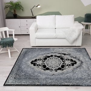 May include: A black and silver area rug with a distressed, vintage look. The rug has a large, intricate medallion design in the center.