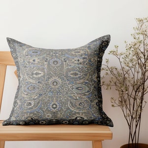 May include: A decorative throw pillow with a blue and gray paisley pattern. The pillow is sitting on a wooden chair.