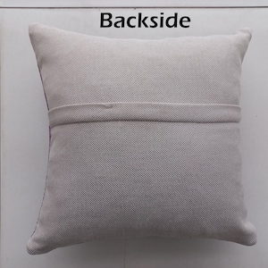 K&ouml;nnte beinhalten: Ein quadratisches, hellgraues Kissen mit strukturiertem Stoff. Das Wort "Backside" ist oben in Schwarz aufgedruckt. Ein horizontales Band aus dem gleichen Stoff ist in der Mitte angen&auml;ht. Die Kanten sind abgerundet.