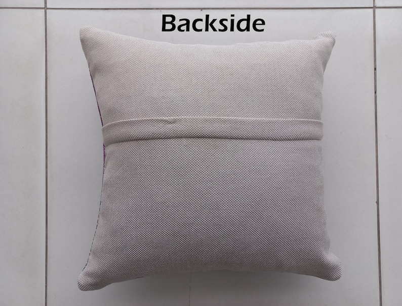 K&ouml;nnte beinhalten: Ein quadratisches, hellgraues Kissen mit strukturiertem Stoff. Das Wort "Backside" ist oben in Schwarz aufgedruckt. Ein horizontales Band aus dem gleichen Stoff ist in der Mitte angen&auml;ht. Die Kanten sind abgerundet.