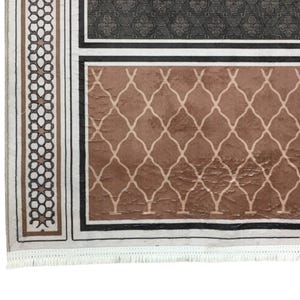 a close-up view of a decorative rug with a geometric pattern in shades of brown and black.