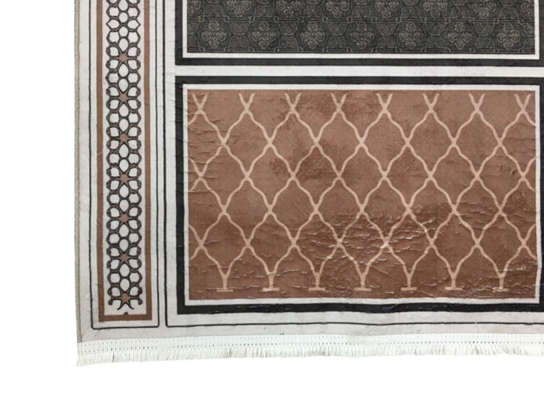 a close-up view of a decorative rug with a geometric pattern in shades of brown and black.