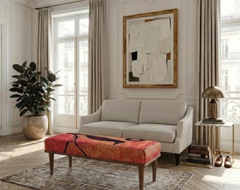 May include: A living room scene featuring a red and orange patterned bench with dark wooden legs. A light-colored sofa sits behind the bench, with a large abstract painting on the wall. A potted plant and side table complete the decor.