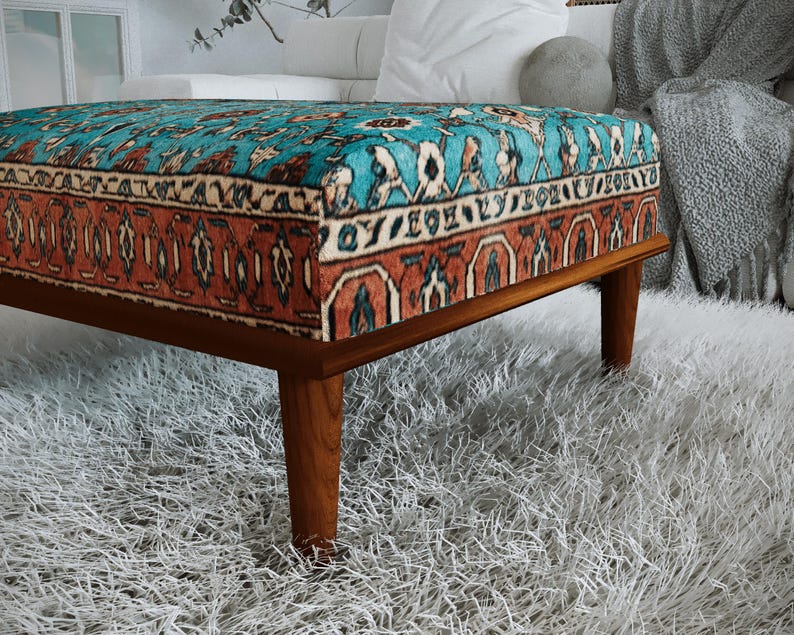 a modern, wooden ottoman with a vibrant, patterned cushion on top, placed on a fluffy white rug.