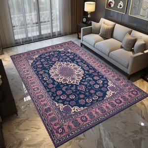 May include: A rectangular area rug with a central floral medallion design in cream and purple, set against a deep blue background. The rug features a border in shades of pink and purple, with floral and scroll patterns. The rug is placed on a marble floor.