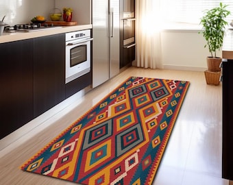 May include: A rectangular runner rug featuring a vibrant geometric pattern of interlocking diamonds in shades of red, yellow, teal, and white. The rug is positioned on a light-colored floor in a kitchen setting with dark cabinets and stainless steel appliances.