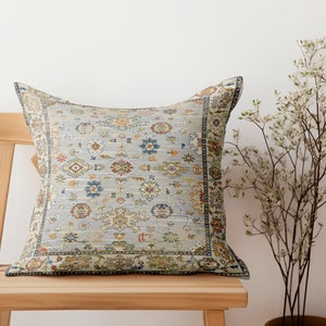 May include: A decorative throw pillow with a light blue background and a colorful floral pattern. The pillow is sitting on a wooden chair.