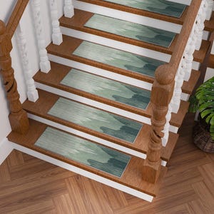 May include: A wooden staircase with six steps, each adorned with a rectangular runner. The runners feature a watercolor-style design in shades of teal and green. The staircase has a wooden handrail and white balusters. A potted plant sits nearby.