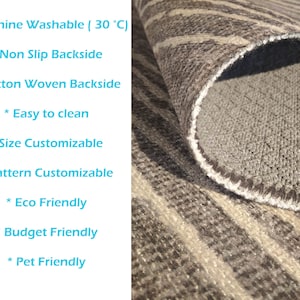 May include: A close-up of a rug with a grey and white striped pattern. The rug has a non-slip cotton woven backing. The rug is machine washable at 30 degrees Celsius. The rug is also eco-friendly, budget-friendly, and pet-friendly.
