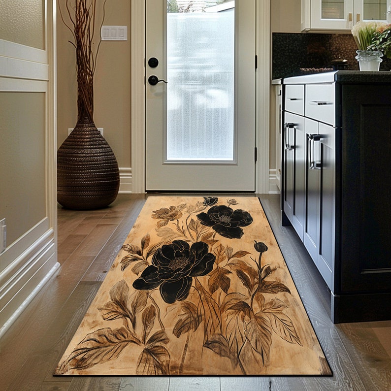 May include: A black and brown floral patterned rug with a beige background. The rug has a long, rectangular shape and features large black flowers with brown leaves.
