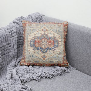 Puede incluir: Una almohada decorativa con un patr&oacute;n colorido e intrincado que recuerda a una alfombra tradicional. La almohada presenta un dise&ntilde;o central en tonos azules, rojos y beige, rodeado de un borde de formas geom&eacute;tricas.