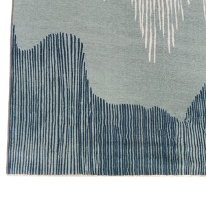 May include: Close-up of a blue and white patterned rug with a textured surface. The rug has a geometric design with vertical lines and wavy shapes.