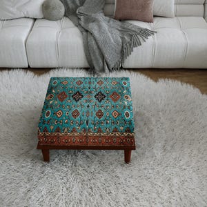 a cozy living room with a plush white rug, a white sofa, and a colorful patterned ottoman in the center of the room.