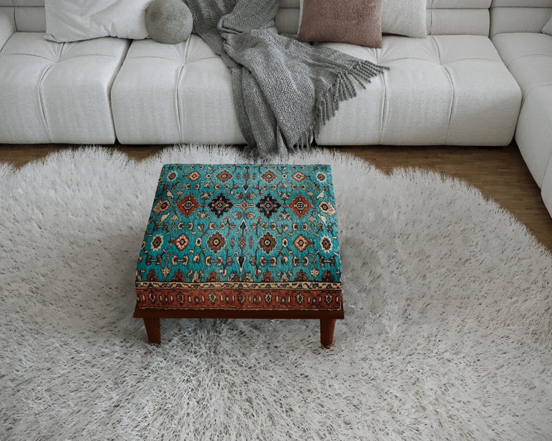 a cozy living room with a plush white rug, a white sofa, and a colorful patterned ottoman in the center of the room.