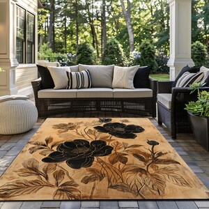 May include: A beige and black floral area rug with a large black flower design. The rug is on a patio with wicker furniture.