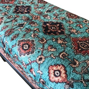 a close-up view of a vibrant, intricately patterned rug or carpet with a mix of geometric and floral designs in shades of blue, red, and orange.