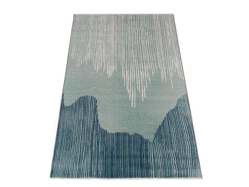 May include: Abstract area rug with a blue and white striped pattern. The rug has a light blue background with white stripes and a darker blue border with white stripes.
