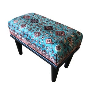 A colorful, patterned ottoman or footstool with a blue and green floral design.