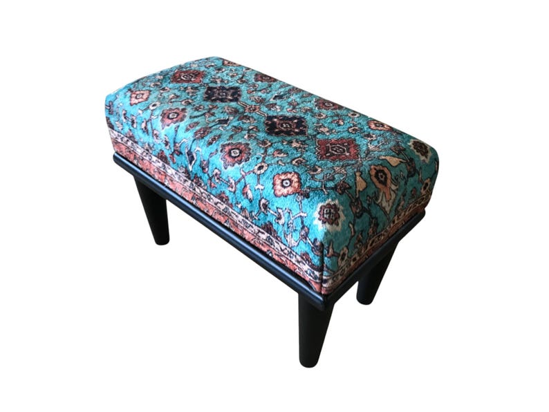 A colorful, patterned ottoman or footstool with a blue and green floral design.