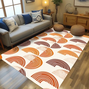 May include: A white area rug with a geometric pattern of orange and brown semi-circles. The rug is on a hardwood floor in a living room setting.