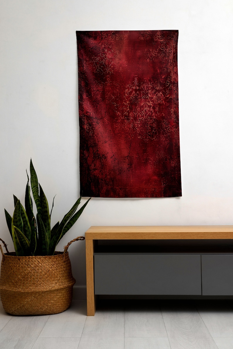 May include: A red tapestry with a vintage floral pattern hangs on a white wall above a wooden media console with two gray drawers.