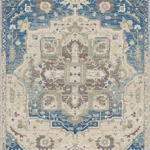 Puede incluir: Alfombra rectangular con un dise&ntilde;o tradicional intrincado. La alfombra presenta un medall&oacute;n central en tonos beige, marr&oacute;n y azul, rodeado por un borde de patrones azules y beige. La est&eacute;tica general es vintage y ornamentada.