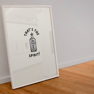 May include: A white framed print with a black and white illustration of a bottle with the text "That's the spirit!"