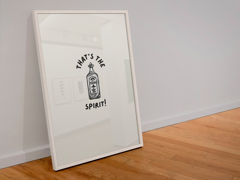 May include: A white framed print with a black and white illustration of a bottle with the text "That's the spirit!"