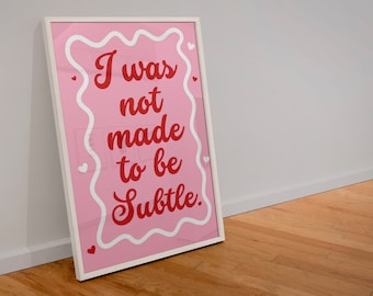 May include: A pink framed poster with white hearts and a white border around the edges. The poster has a red cursive message that reads "I was not made to be Subtle."