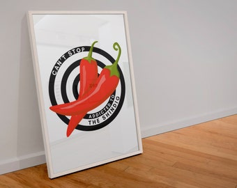May include: A white framed print with a black and white target design and two red chili peppers. The text "Can't Stop Addicted to the Shindig" is written around the target.