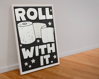 May include: A black and white framed print with the text "ROLL WITH IT." and a cartoon image of a toilet paper roll.