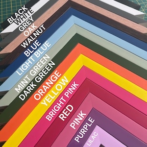 May include: A variety of picture frame moulding samples in different colors, including black, white, grey, oak, walnut, blue, light blue, mint green, dark green, orange, yellow, bright pink, red, pink, purple, and lilac.