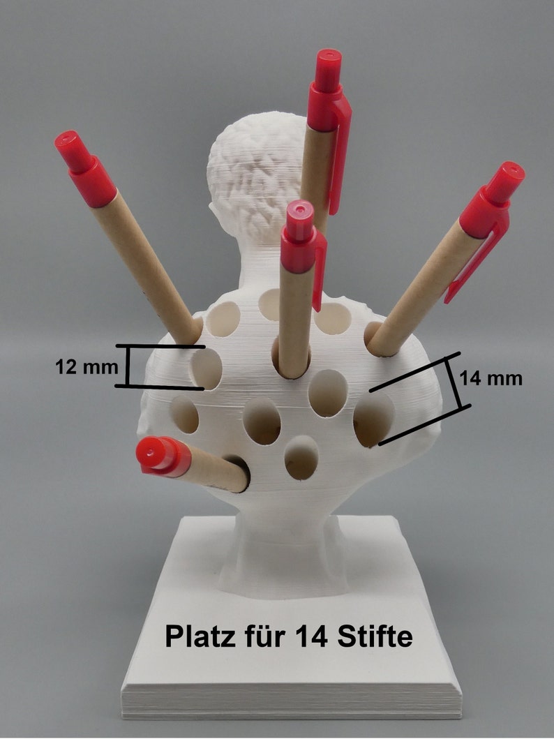 K&ouml;nnte beinhalten: Wei&szlig;er Plastik-Stiftst&auml;nder in Form einer B&uuml;ste mit 14 L&ouml;chern f&uuml;r Stifte. Die L&ouml;cher sind 12 mm breit und 14 mm tief. Der St&auml;nder hat den Text "Platz f&uuml;r 14 Stifte" auf der Basis.