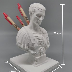 K&ouml;nnte beinhalten: Wei&szlig;e 3D-gedruckte B&uuml;ste eines r&ouml;mischen Kaisers mit einem Stifthalter auf der R&uuml;ckseite. Die B&uuml;ste ist 20 cm hoch, 13 cm breit und 12 cm tief. Die B&uuml;ste steht auf einem quadratischen Sockel.