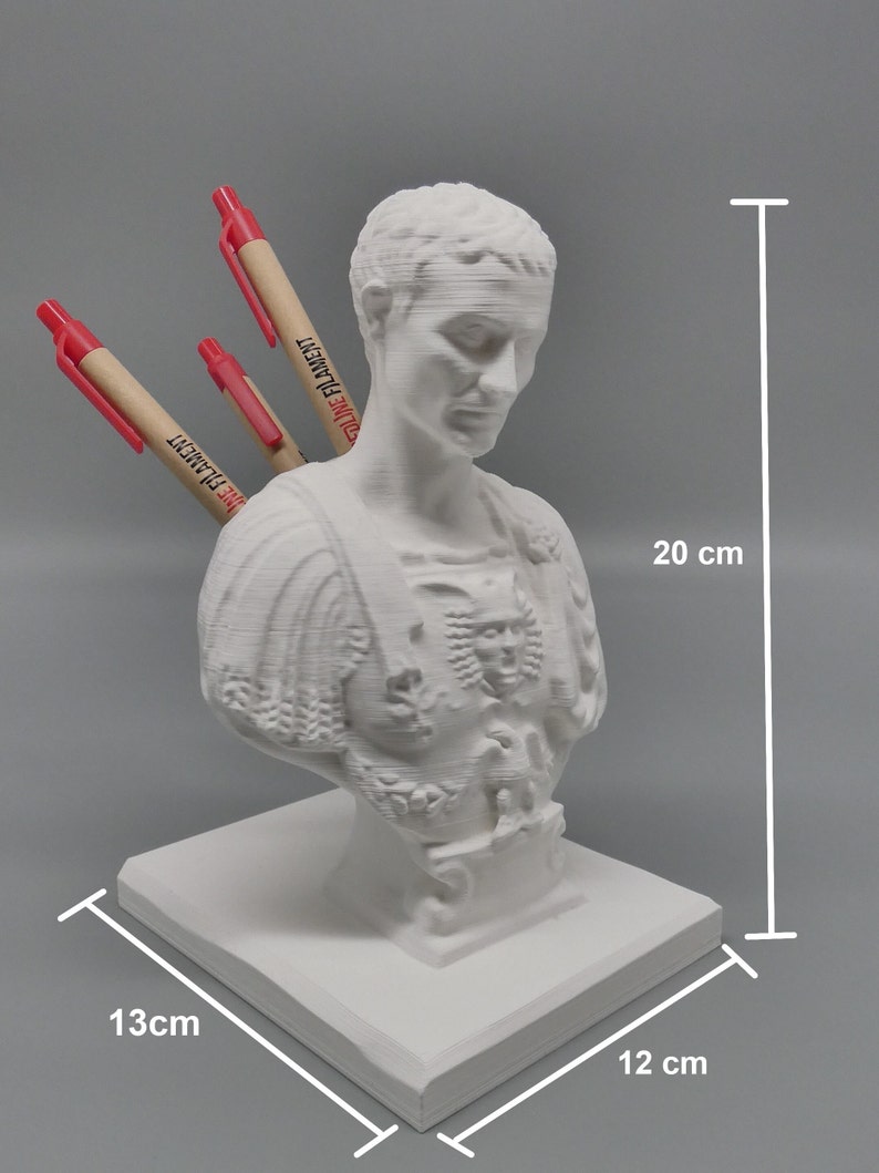K&ouml;nnte beinhalten: Wei&szlig;e 3D-gedruckte B&uuml;ste eines r&ouml;mischen Kaisers mit einem Stifthalter auf der R&uuml;ckseite. Die B&uuml;ste ist 20 cm hoch, 13 cm breit und 12 cm tief. Die B&uuml;ste steht auf einem quadratischen Sockel.